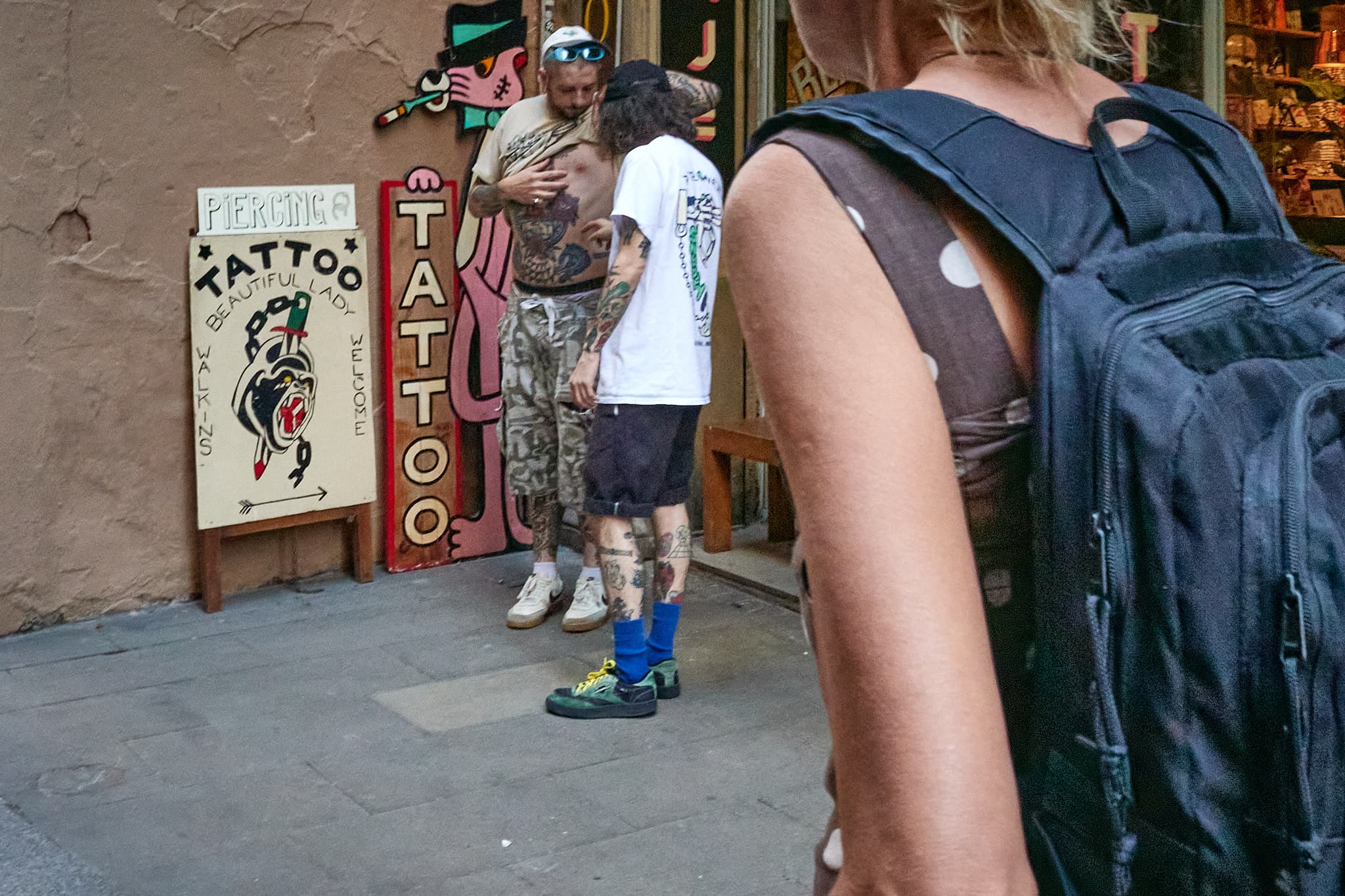 A layered street scene outside a tattoo shop