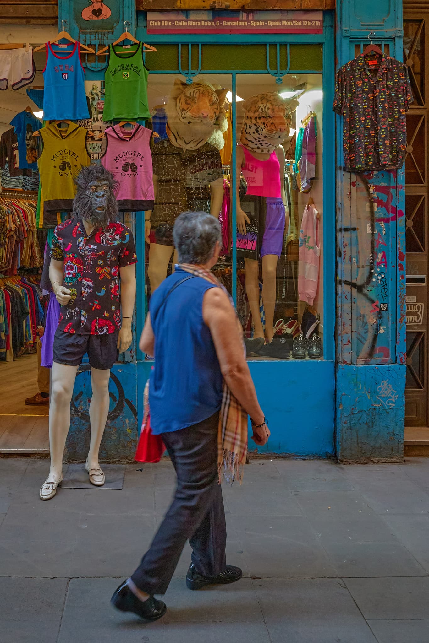 A passerby crossing a colorful vintage clothing shop window